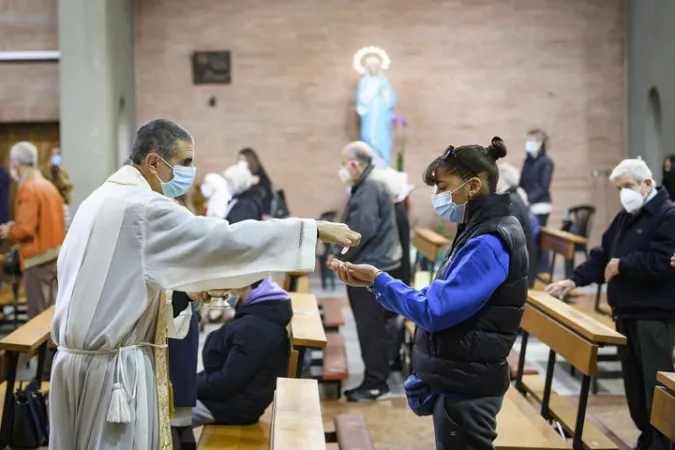 Sacerdote mentre dà la comunione in mano a un fedele | CEI