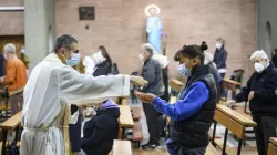 Sacerdote mentre dà la comunione in mano a un fedele / CEI