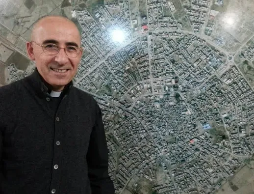 Don Georges Jahola nel suo ex ufficio ad Erbil davanti alla mappa di Baghdeda |  | KIN