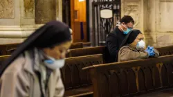 Fedeli pregano con mascherina in chiesa / LN