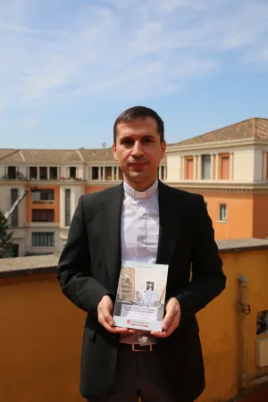 Padre Rebwar Basa, autore del libro su Padre Ragheed, posa con il libro nella sede italiana di Aiuto alla Chiesa che Soffre, Roma, 1 giugno 2017 | Mary Shovlain / ACI Group